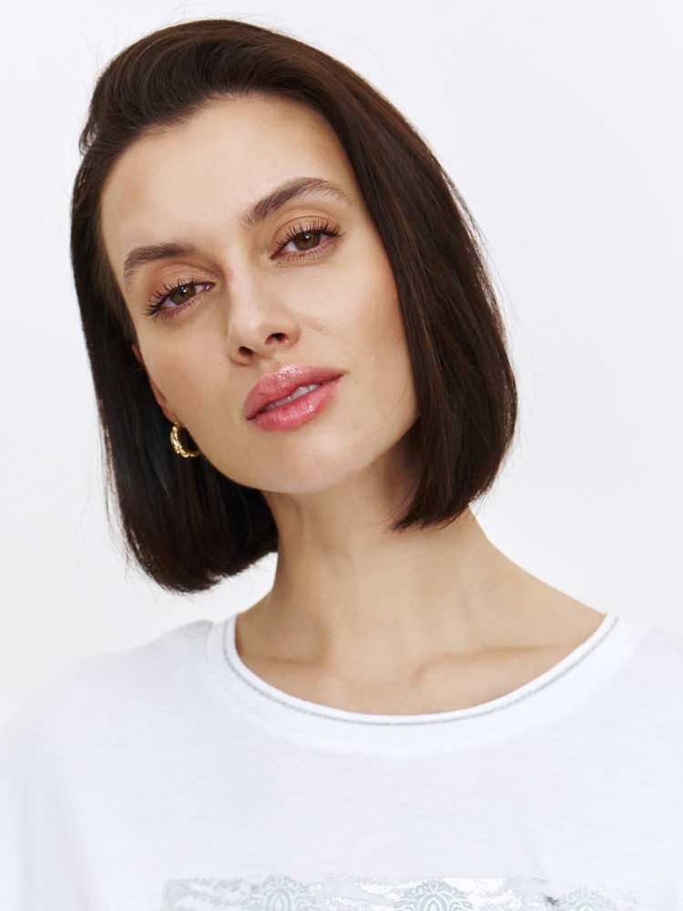 Biały top ze srebrnym nadrukiem na środku 