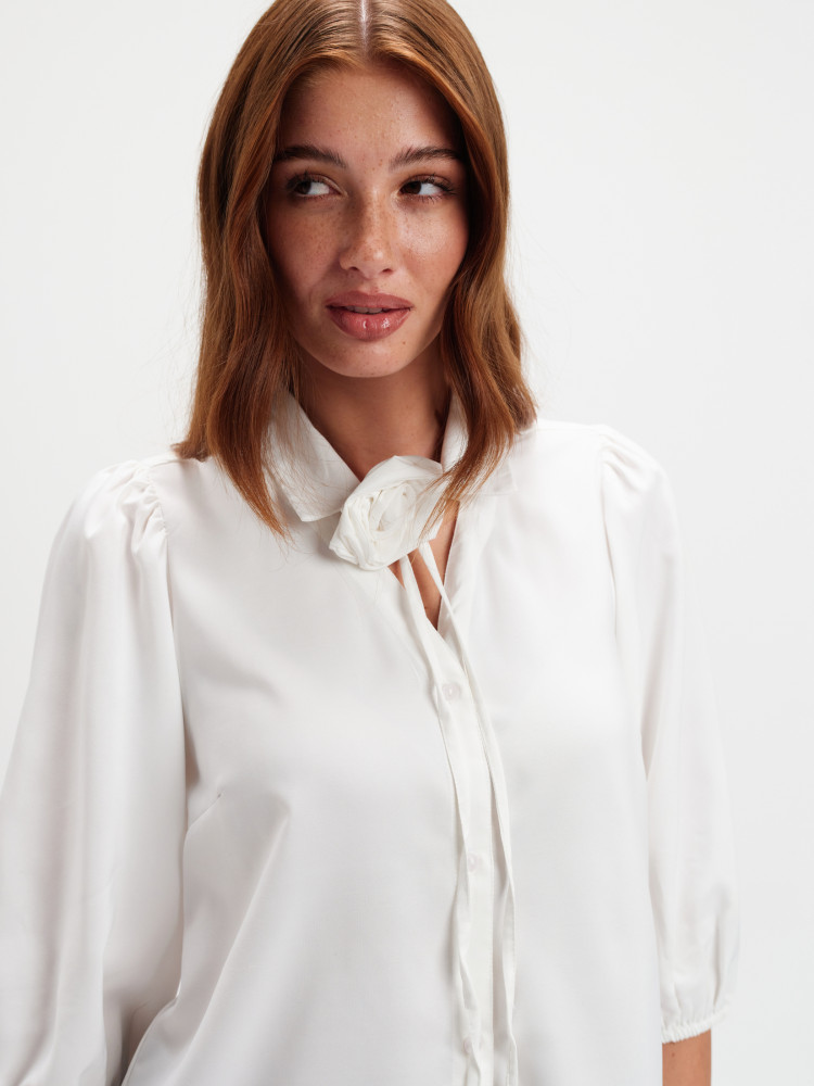 Biała bluzka z dekoracyjnym kwiatem 