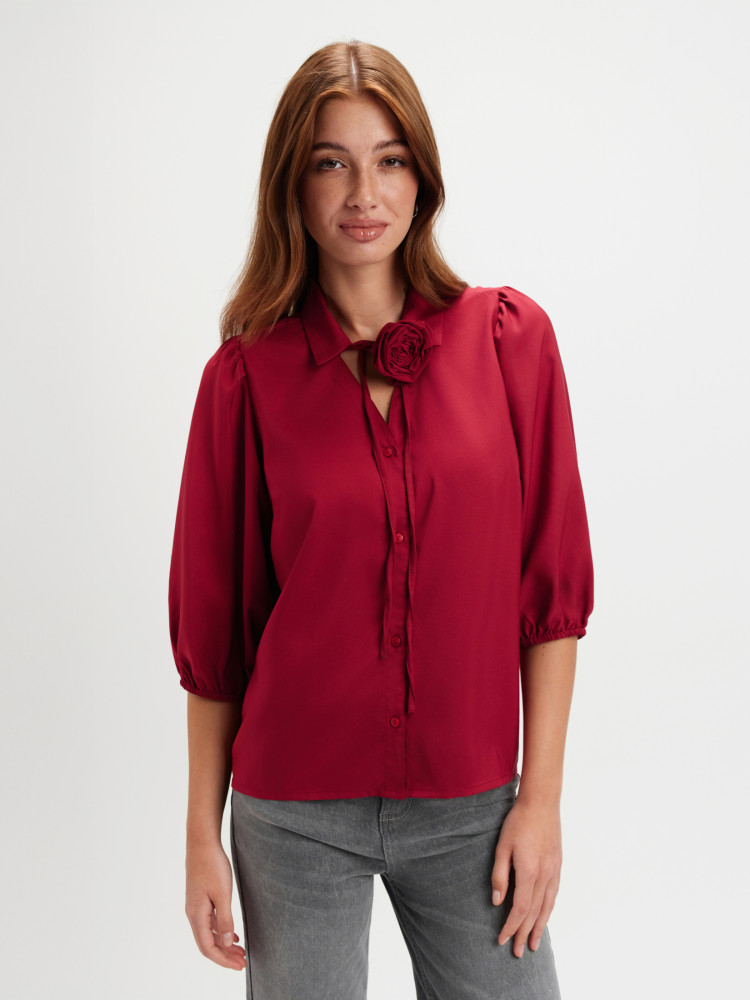 Czerwona koszula z kwiatem przy dekolcie 