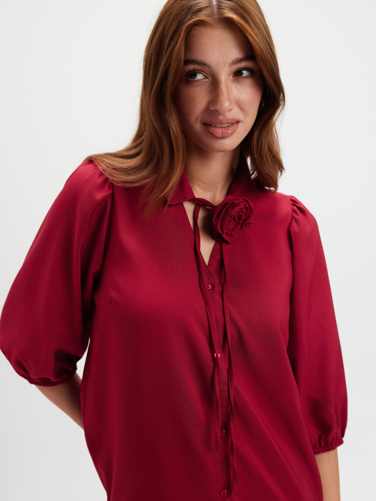 Czerwona koszula z kwiatem przy dekolcie 