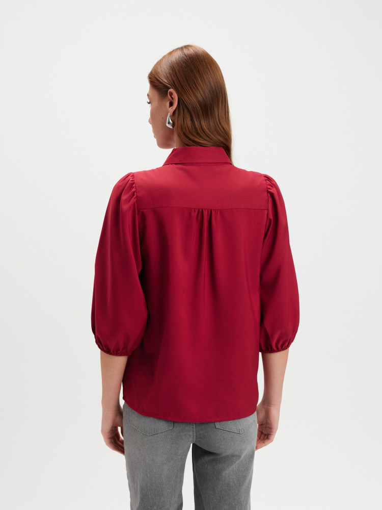 Czerwona koszula z kwiatem przy dekolcie 